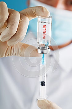 The doctor holds a syringe for injections and an ampoule with insulin for the treatment of Diabetes