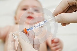 Doctor holds syringe to vaccinate baby