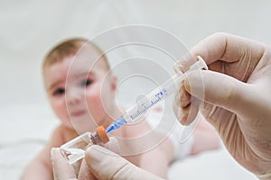 Doctor holds syringe to vaccinate baby with injection