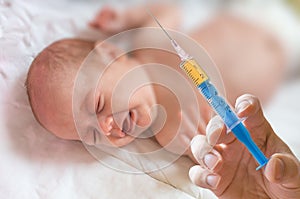 Doctor holds syringe to vaccinate sick baby with injection