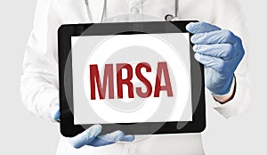 Doctor in holds a tablet with text MRSA photo