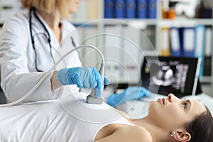 Doctor holds ultrasound probe on chest of patient in clinic closeup