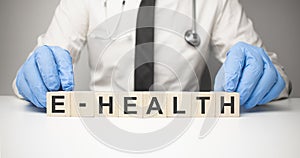 Doctor holds wooden cubes in his hands with text E health