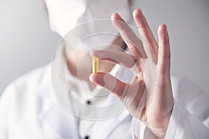 Doctor holds yellow pill in his hand. Medical concept
