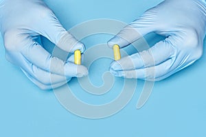 Doctor holds yellow pills in his hands. medical worker in gloves. pharmacology. blue background