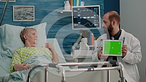 Doctor with horizontal green screen on tablet talking to patient