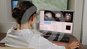 Doctor in Hospital Examining computer display or monitor while patient undergoing MRI brain procedure. MRI scanning