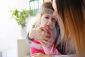 Doctor hugging scared crying little baby girl visiting her office