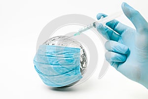 Doctor injecting coronavirus vaccine to globe covered with medical face mask on white background