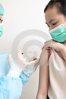 Doctor injecting flu or COVID-19 vaccine by injection into child girl body with a syringe to treat and produce immunity against