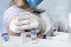 doctor is injecting medicine for treatment or a vaccine to prevent corona virus or Covid 19 in the arms of an girl. Large-scale