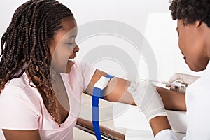 Doctor Injecting Patient With Syringe To Collect Blood