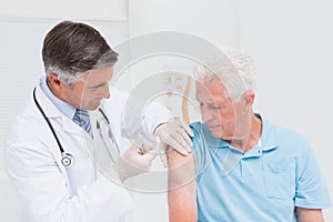 Doctor injecting senior patient in clinic photo