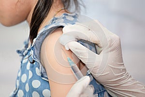 Doctor injecting vaccination in arm of asian little child girl