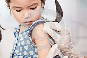 Doctor injecting vaccination in arm of asian little child girl