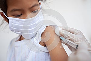 Doctor injecting vaccination on asian child girl arm. The child girl wearing protection mask for protect air smog pollution