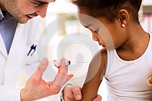 Doctor injecting vaccine to cute african girl photo
