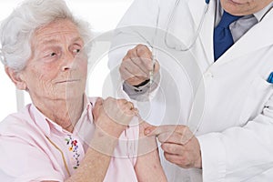 Doctor injecting vaccine to senior woman photo