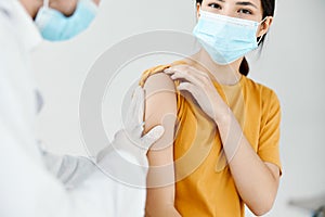doctor injecting a woman in a yellow t-shirt in the shoulder close-up covid vaccination