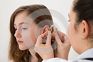 Doctor Inserting Hearing Aid In The Ear Of A Girl