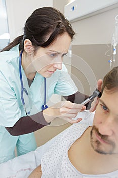 Doctor inserting hearing aid in mans ear