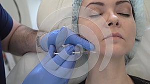 A doctor inserts painkillers into the chin area of womans face