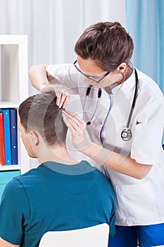 Doctor inspecting skin of head