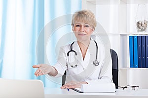 Doctor inviting patient on a chair photo