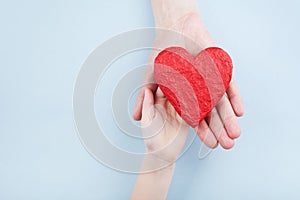 Doctor and kid holding red heart in hands. Family relationships, health care, pediatric cardiology concept. photo