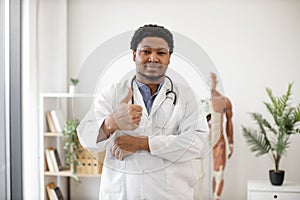 Doctor in lab coat giving thumb-up on clinic background
