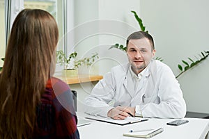 A doctor in lab coat is listening to a female patient`s complaints in a hospital