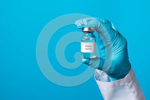 A doctor or lab technician in blue gloves holds a rabies vaccine with a place to text. Prevention in veterinary medicine. Rabies