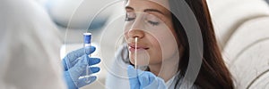 Doctor laboratory assistant in protective suit takes swab from nose of sick patient at home