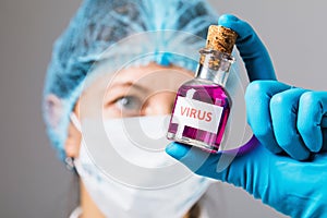 The doctor in the laboratory holds a bottle with the virus in his hands. Concept on the illicit manufacture of toxic substances