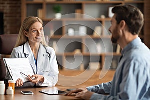 Doctor Lady Showing Medical Test Results To Male Patient In Clinic Office