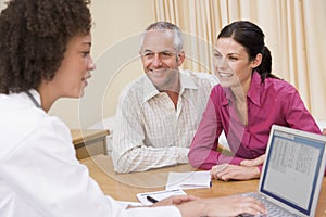 Doctor with laptop and couple in doctor's office