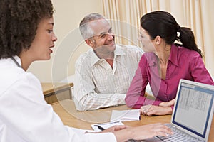 Doctor with laptop and couple in doctor's office