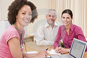 Doctor with laptop and couple in doctor's office