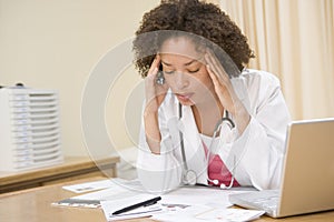 Doctor with laptop and headache in doctor's office