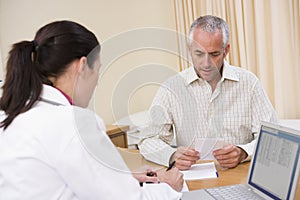 Doctor with laptop and man in doctor's office