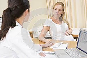 Doctor with laptop and pregnant woman photo