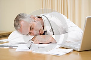 Doctor with laptop sleeping in doctor's office