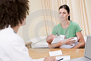 Doctor with laptop and woman in doctor's office photo