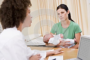 Doctor with laptop and woman in doctor's office photo