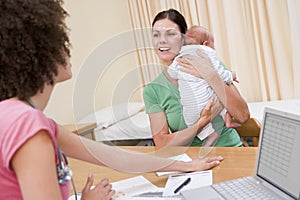 Doctor with laptop and woman in doctor's office