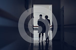 Doctor is leading woman with stick through hallway