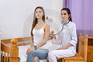 Doctor listening patient`s heartbeat with stethoscope in hospital