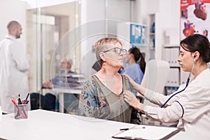 Doctor listening senior woman heart