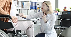 Doctor listening with stethoscope to fetal heartbeat to pregnant woman in wheelchair in clinic 4k movie