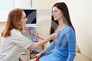 Doctor listening stethoscope with to heart of young female patient